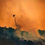 Fire fighting helicopter carry water bucket to extinguish the forest fire.